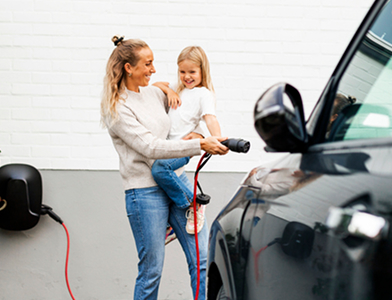 person with child , charging an electric vehicle