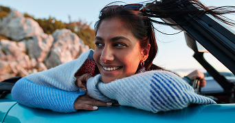 person leaning on car with hands folded under chin
